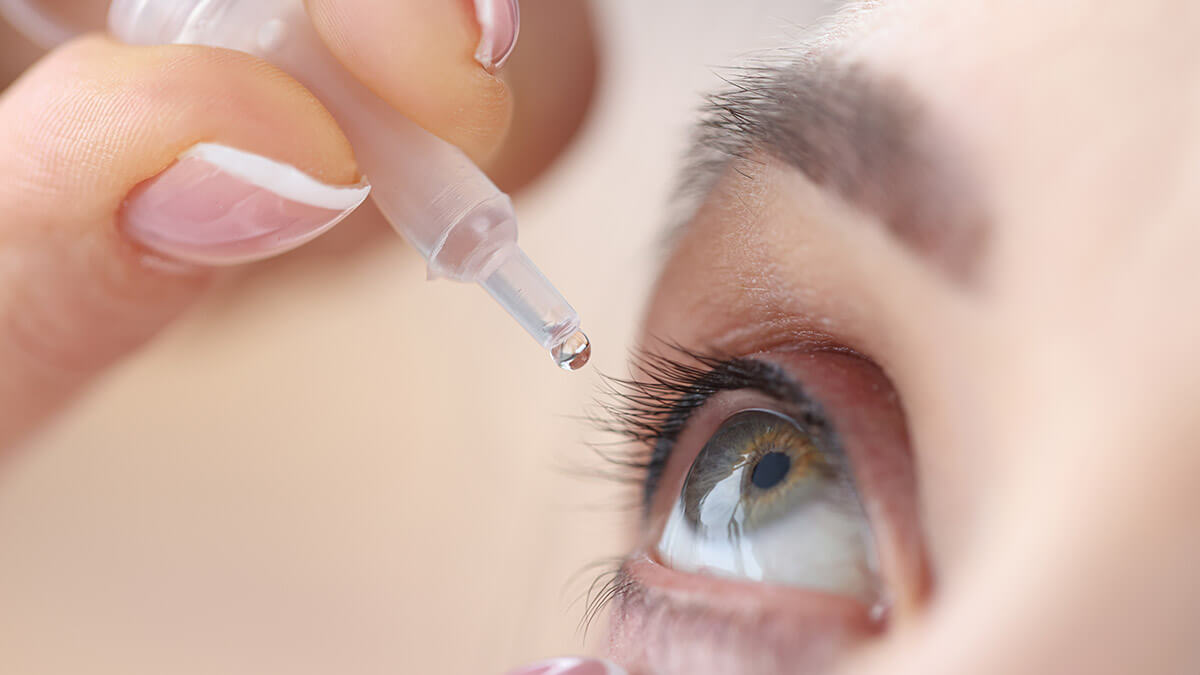 Close up of woman using eye drops.